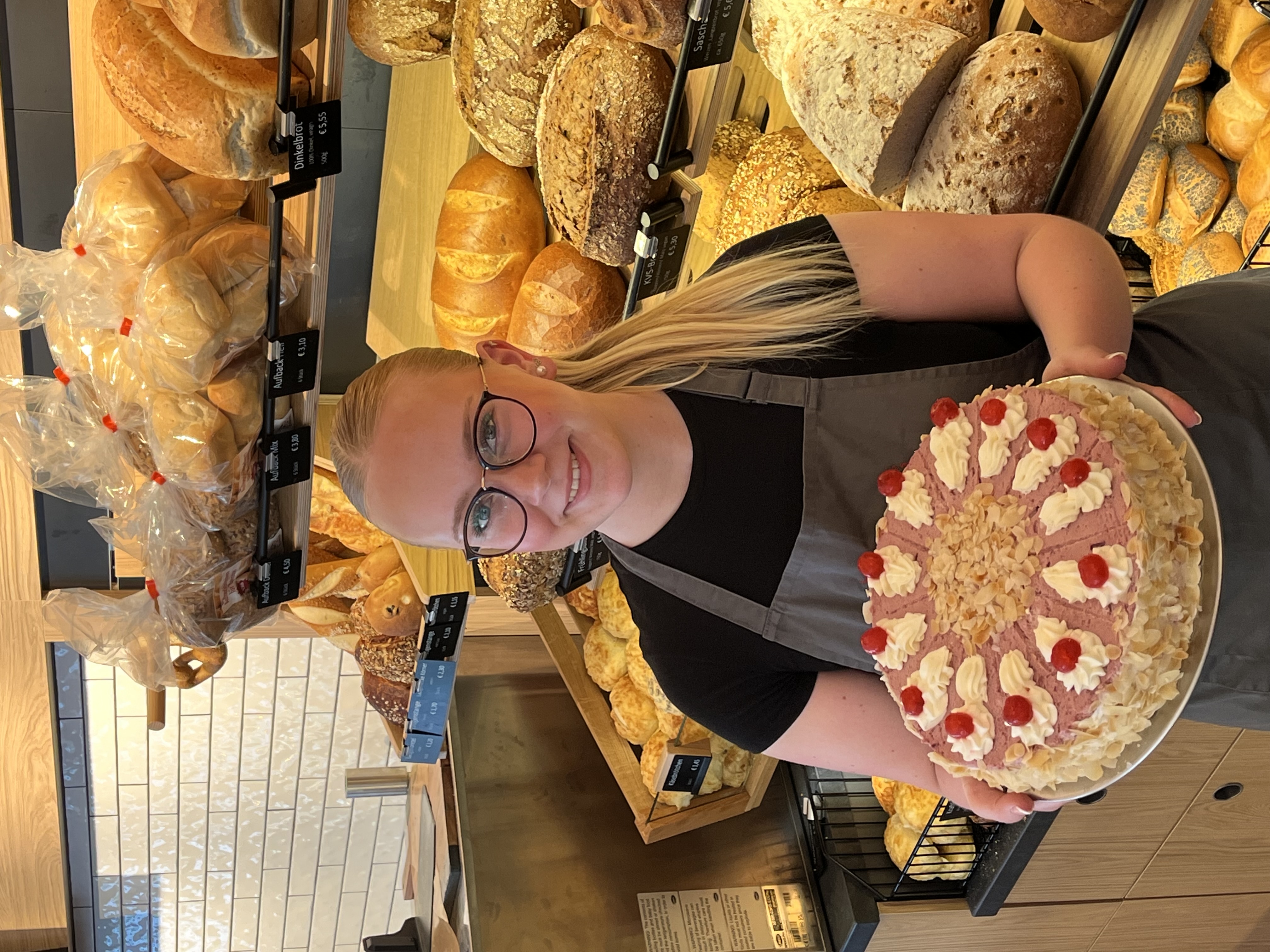 Mitarbeiterin der Bäckerei Schwabe mit einer frisch dekorierten Torte